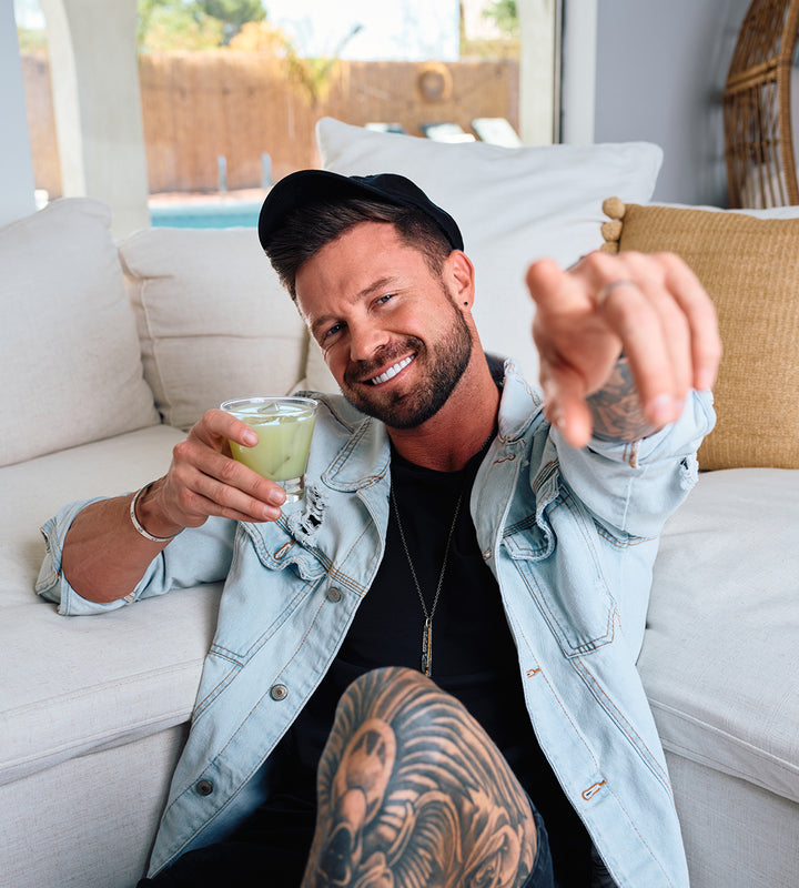SIP Elixirs - Tattoo'd man enjoying a cocktail and pointing